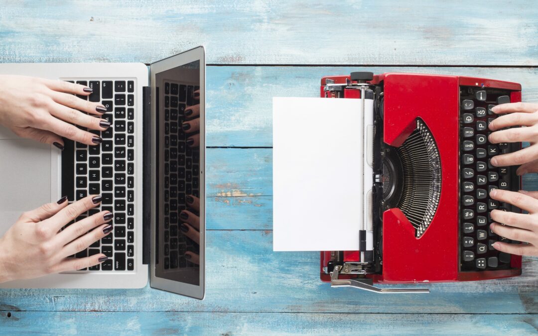 Ariel view of red typewriter and MacBook on blue wood desk